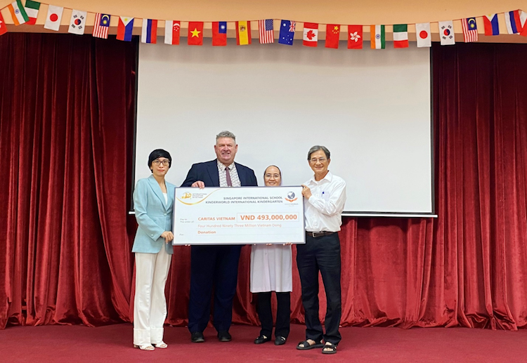 Thầy Mark Priddis - Hiệu Trưởng trường Quốc tế Singapore tại Nam Sài Gòn và bà Phạm Minh Hồng - Giám Đốc KinderWorld khu vực phía Nam trao số tiền thiện nguyện cho đại diện Caritas Việt Nam.