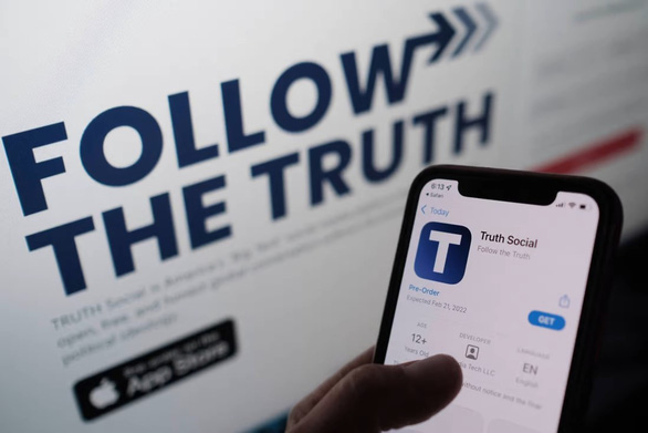 Một người dùng đang kiểm tra về app Truth Social trên kho ứng dụng App Store so với thông tin trên trang web của mạng xã hội này - Ảnh: AFP