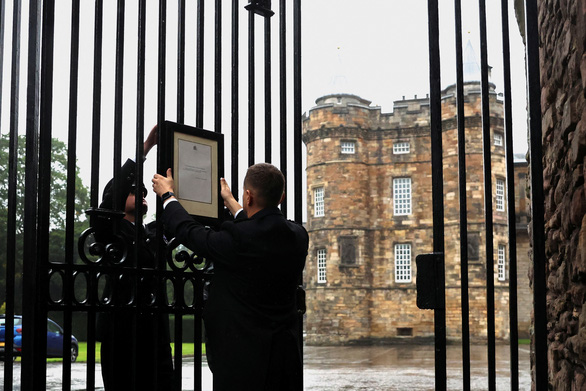 Nhân viên ở lâu đài Holyroodhouse, tại Holyrood, thành phố Edinburgh, Scotland gắn thông báo về sự qua đời của Nữ hoàng Elizabeth II vào ngày 8-9 - Ảnh: REUTERS