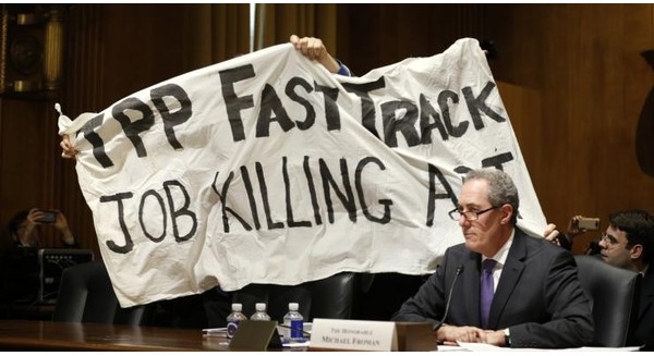 Một người biểu tình phản đối hiệp định TPP đằng sau Đại diện Thương mại Mỹ Micheal Froman