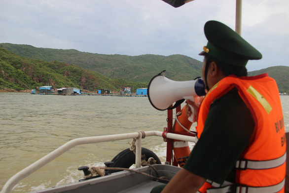 Bộ đội biên phòng Bình Định thông báo lệnh cấm biển và kêu gọi người dân trên các lồng bè nuôi hải sản ở Quy Nhơn chủ động chằng néo, rời bè khi có yêu cầu - Ảnh: NGỌC CHU