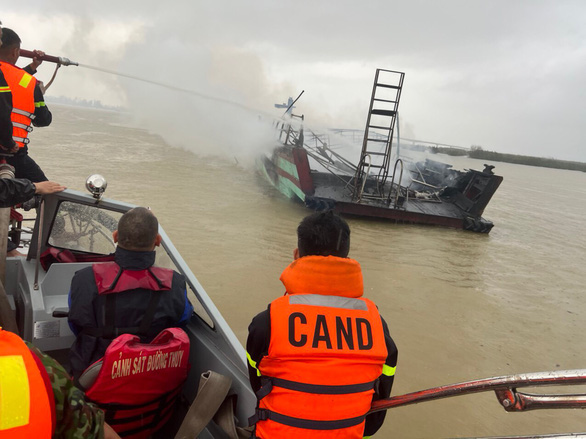 Lực lượng chức năng tiếp cận một tàu gỗ đã bị lửa thiêu rụi - Ảnh: H.A.